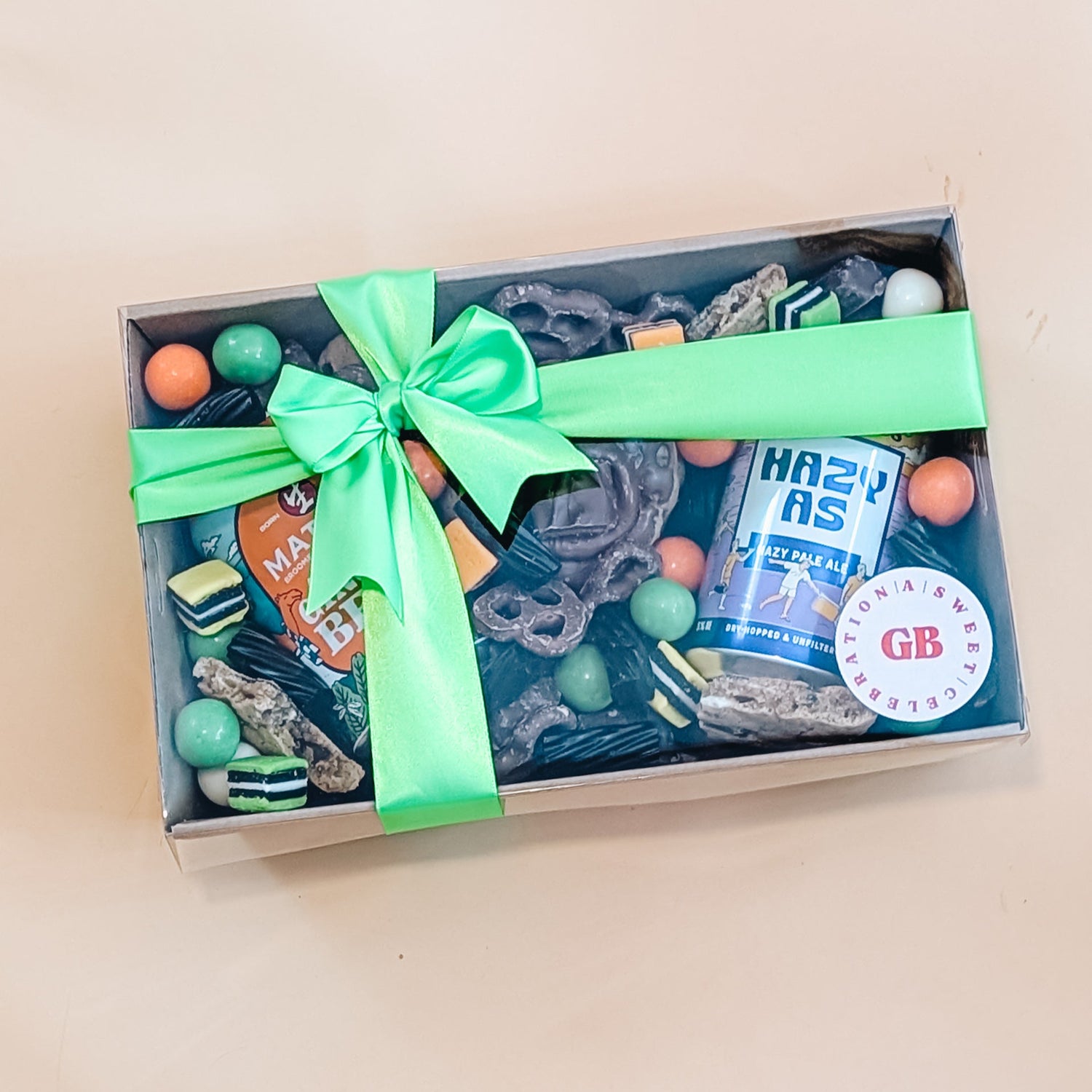 Fathers day gift box with a green ribbon, chocolate, and a bottle of craft beer on a beige background