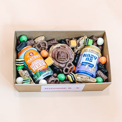 Fathers day box of assorted snacks including cookies, chocolates, and craft beer on a beige background