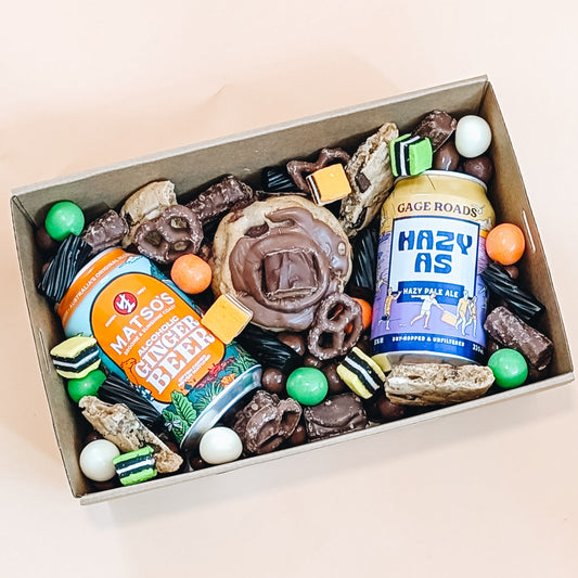 Box of assorted snacks and beer bottles on a light background