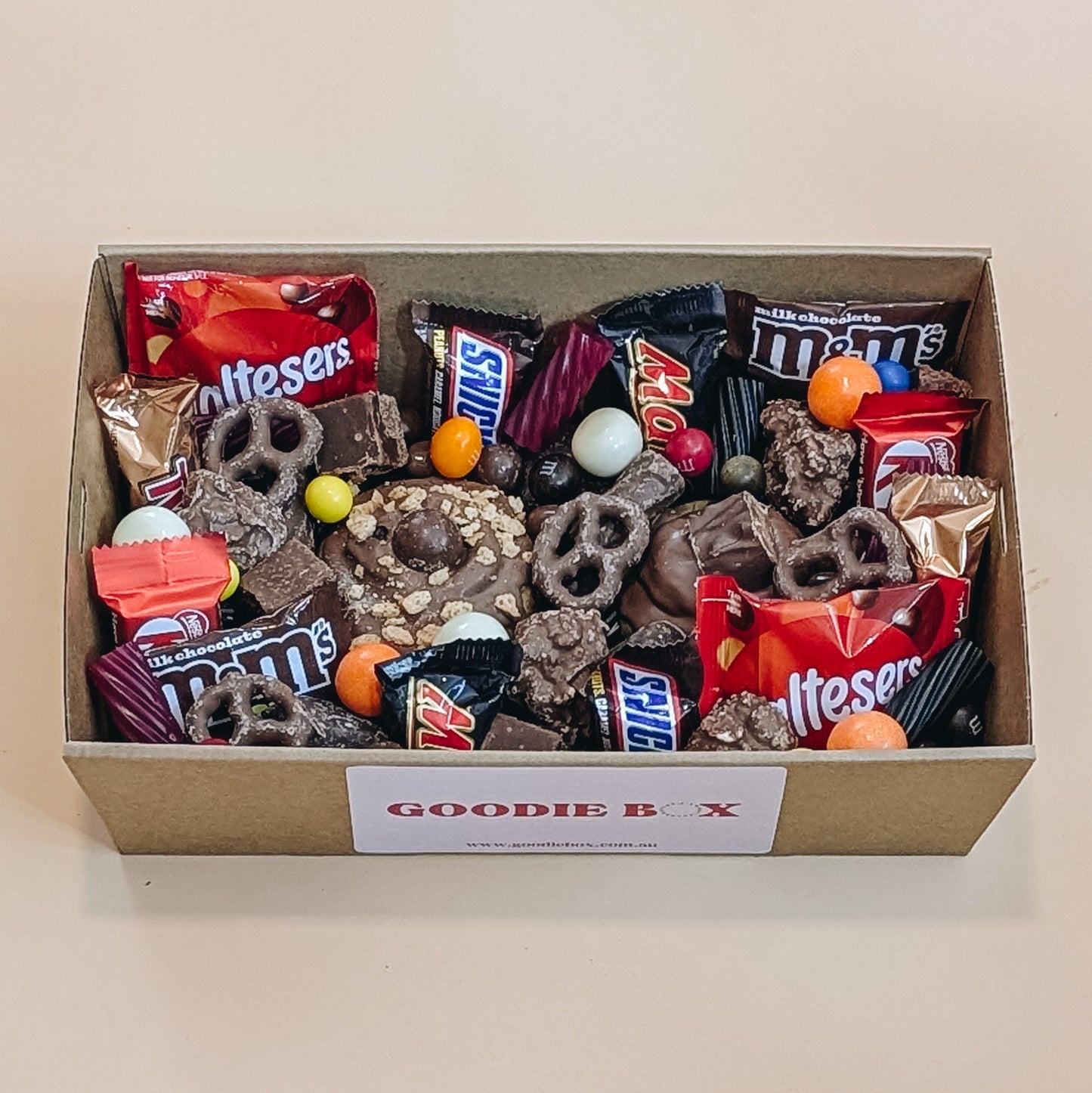 Goodie box filled with various snacks and candies on a beige background