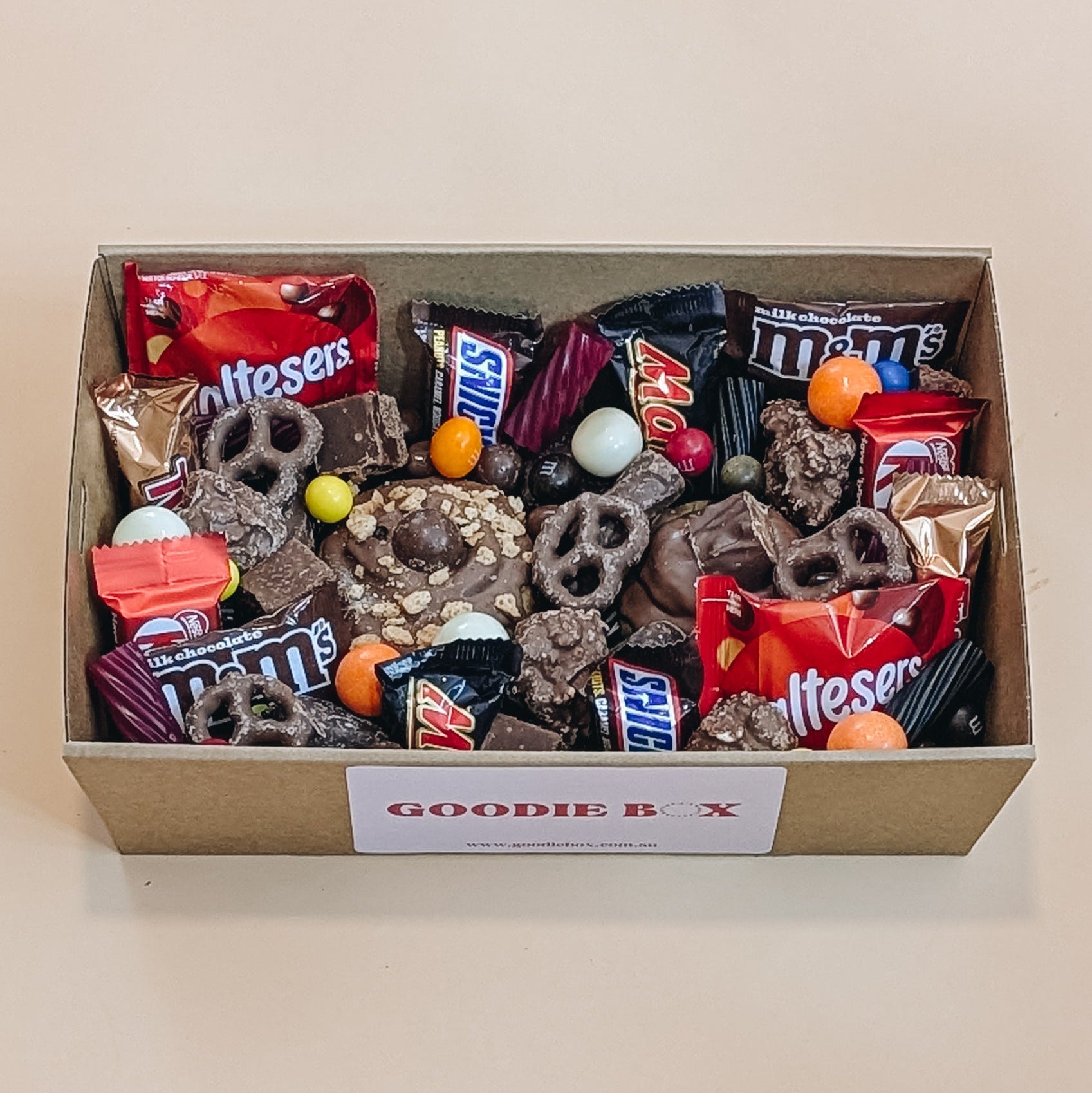 Goodie box filled with various snacks and candies on a beige background