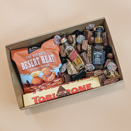 Gift box with snacks, candies, and a bottle of Jack Daniel's on a beige background