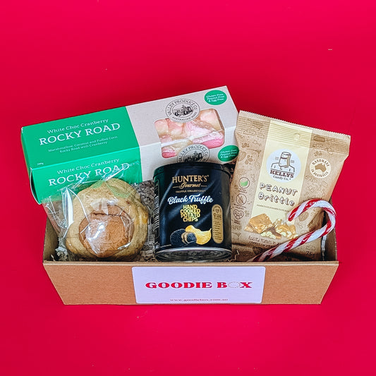 Gift box with rocky road, cookie, chips and peanut brittle on a red background.