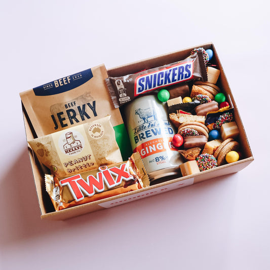 Goodie Box sweet and savoury gift box overhead view with Little Fat Lamb ginger beer, Beef Jerky, Snickers, Twix, Kelly's Peanut Brittle and assorted treats