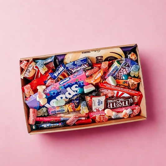 Ultimate chocolate and lolly treat box packed with Nerds, M&Ms, and gummy sweets on a pink background