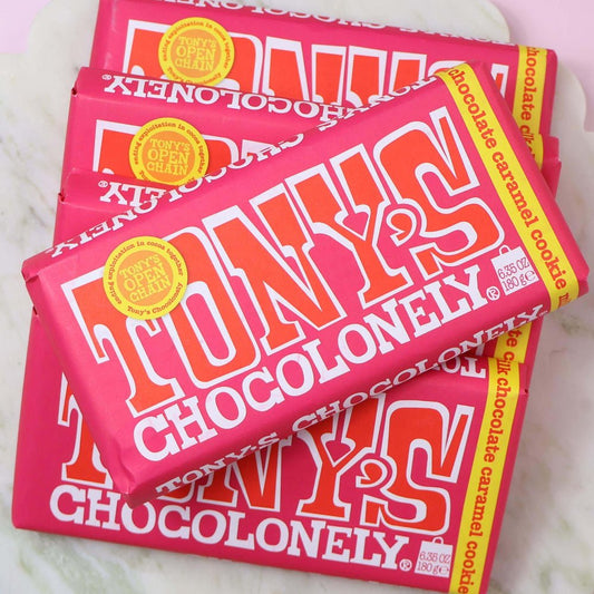 Pink and red Tony's Chocolonely chocolate caramel cookie chocolate bars stacked on a white surface