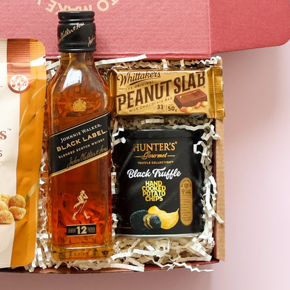 Whisky gift box showing Johnnie Walker Black Label, Whittaker's Peanut Slab and Hunter's Black Truffle Chips 